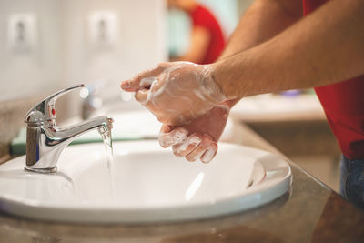 Midsection of woman with faucet in water
