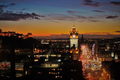 Illuminated cityscape against sky at sunset