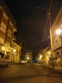 Illuminated street amidst buildings in city at night