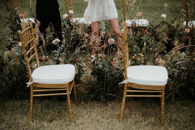 Low section of woman standing on chair in field