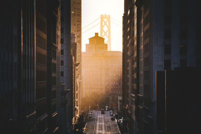 Road amidst buildings in city during sunrise