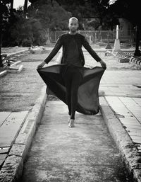 Full length of model walking on pathway against trees in cemetery