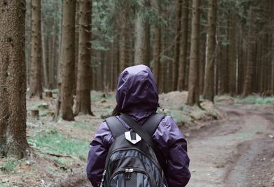 Rear view of woman wearing raincoat while standing in forest