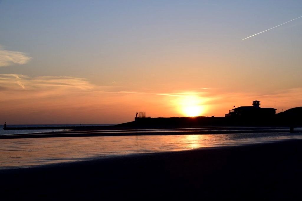 sunset, silhouette, sea, water, beach, sky, orange color, sun, scenics, beauty in nature, tranquil scene, shore, built structure, horizon over water, tranquility, nature, architecture, building exterior, idyllic, reflection