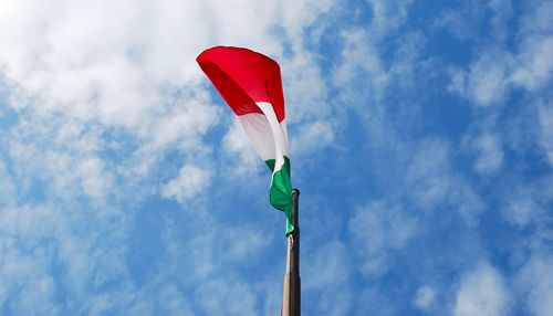 Italian flag isolated on blue sky with clouds background fluttering in the wind.