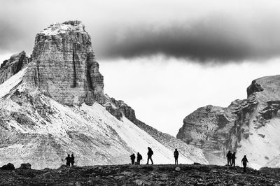 People on cliff against rocky mountains at dolomites