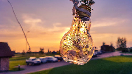Close-up of light bulb against sky during sunset