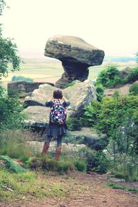 Rear view of man standing on rock against sky