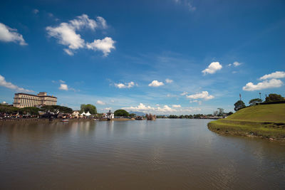 View of city at waterfront against cloudy sky