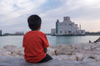 Rear view of boy looking at museum of islamic art doha, qatar. 