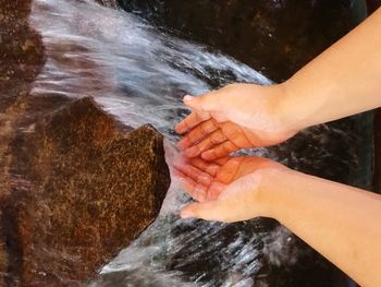 Cropped image of person gesturing below waterfall