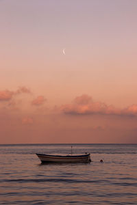 Boat in sea against sky during sunset