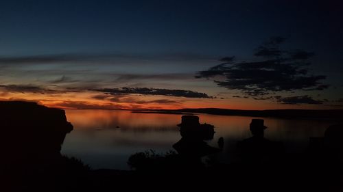 Silhouette trees by lake against sky at sunset