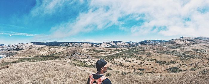 Rear view of people standing on mountain against sky
