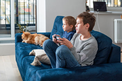 Full length of man and dog on sofa