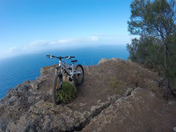 Bicycle by sea against blue sky