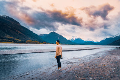 Rear view of woman standing on lake against sky