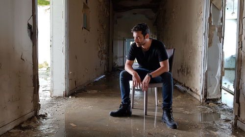 Young man sitting on wall in building