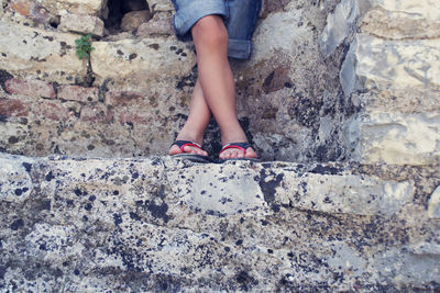 Low section of kid standing on stone wall