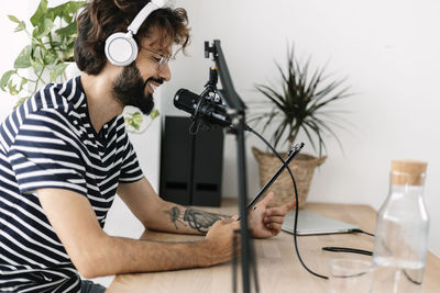 Content creator wearing wireless headphones recording podcast at home studio