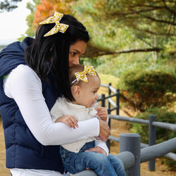 Side view of mother holding daughter on railing