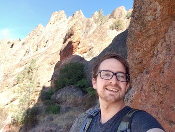 Portrait of smiling man on rock against mountains