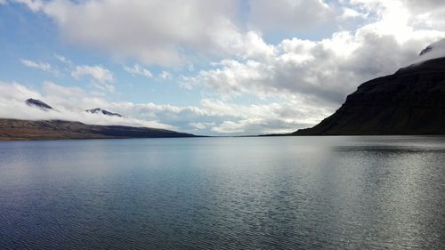 Scenic view of sea by mountains against sky