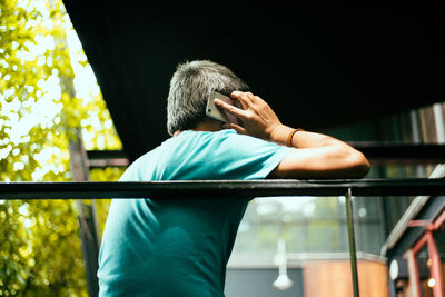 Low angle view of man talking on mobile phone in balcony