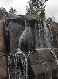 Water flowing through rocks against sky