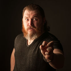 Portrait of man standing against black background