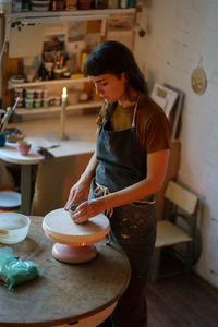 Handicraft ceramic pottery creation, woman artist shaping and molding potter tableware from raw clay