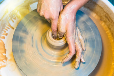 Cropped hands making pottery