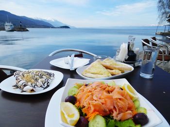 Close-up of food on table by sea against sky