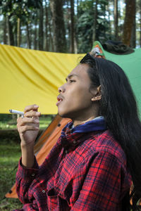 Side view of young woman looking away while standing outdoors