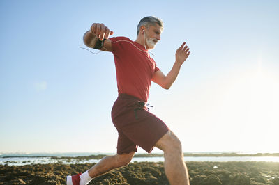 Male jogger running on rocks at beach