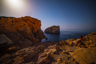 Scenic view of rocks in sea against sky at night