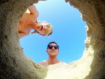 Low angle view of couple against clear sky seen from hole
