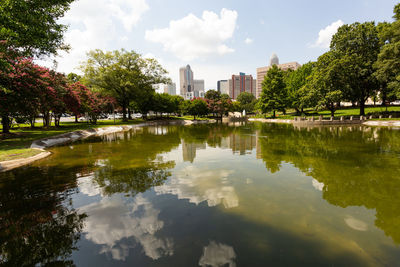 Reflection of trees in lake against sky in city