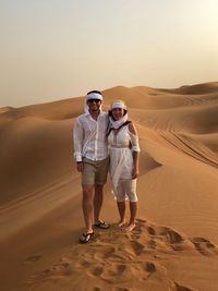 Full length of couple standing on sand dune in desert