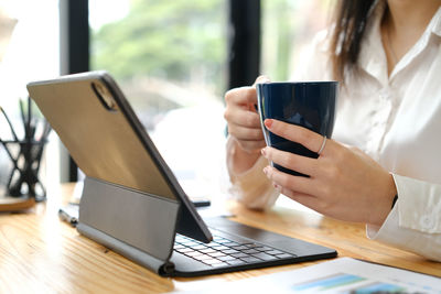 Midsection of woman using mobile phone on table