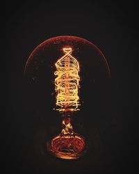 Illuminated light bulb against black background