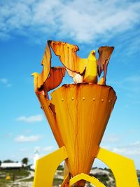 Low angle view of yellow umbrella against blue sky