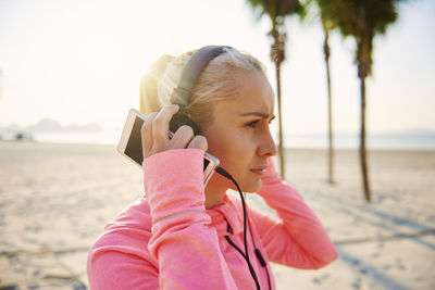 Portrait of young woman with arms raised on beach