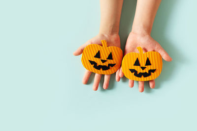 Close-up of hand holding pumpkin against white background