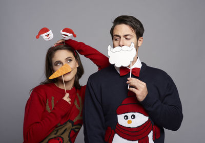 Portrait of man with woman wearing mask against gray background