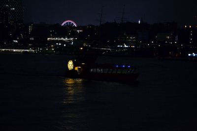 Illuminated bridge over river in city at night