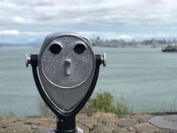 Close-up of coin-operated binoculars against cityscape