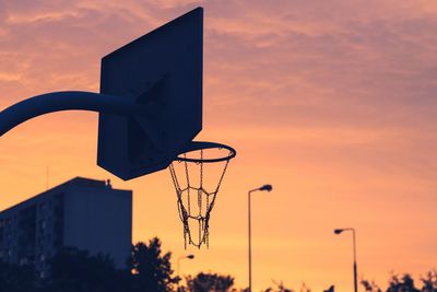 Low angle view of basketball hoop against orange sky