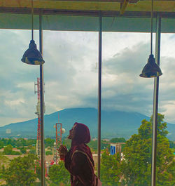 Rear view of men against sky seen through glass