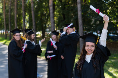 Rear view of woman wearing graduation gown standing in park